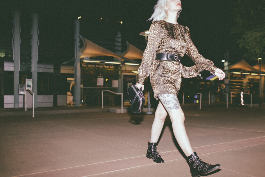 Trina in a leopard dress and studded boots walking